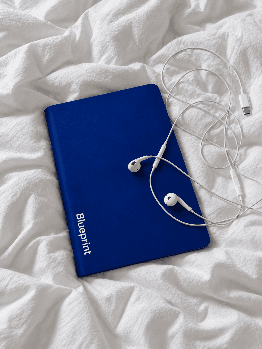 Blueprint fechada sobre um lençol branco, com fones de ouvido